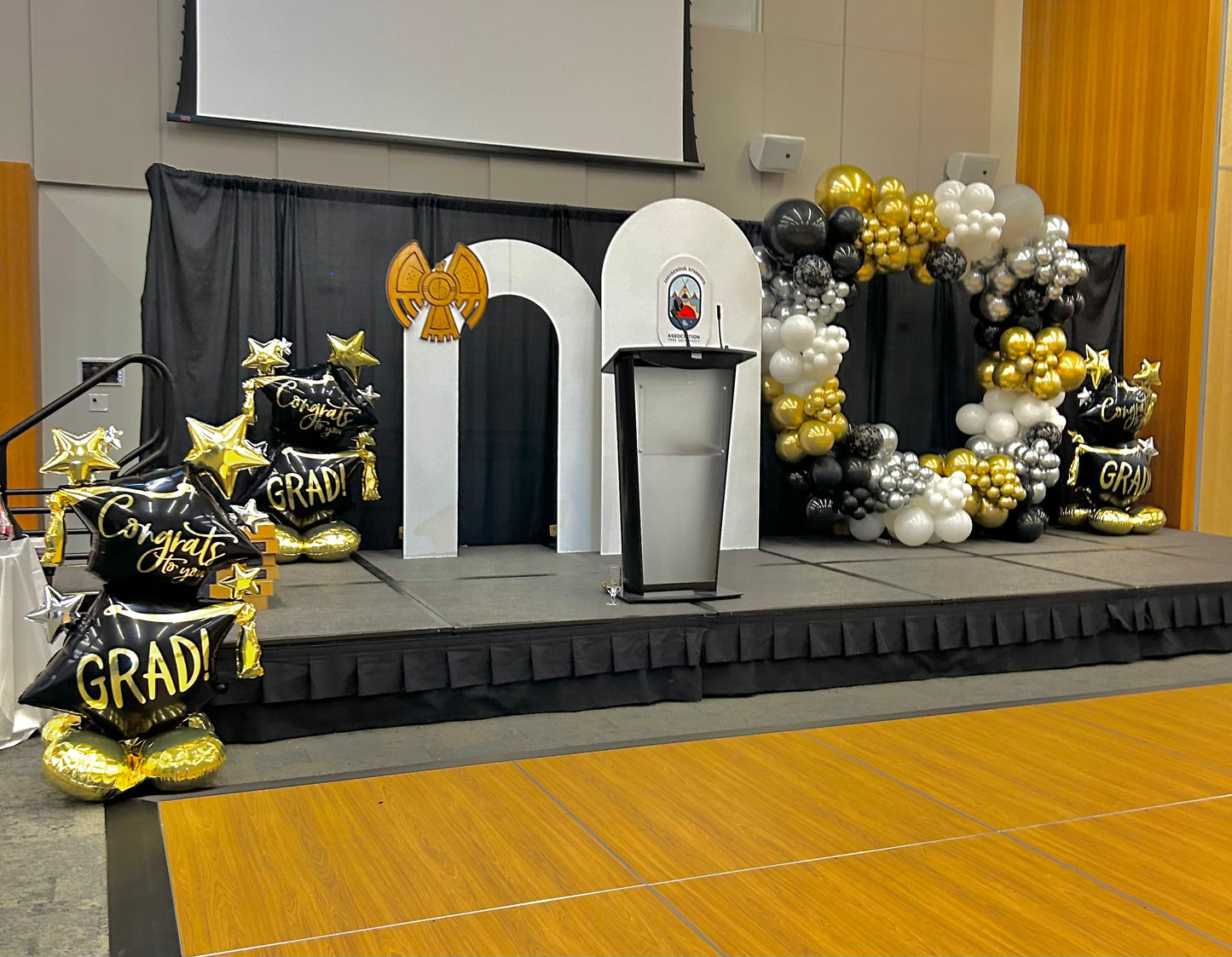 Elegant Graduation Balloon Decor featuring a black, gold, and white balloon arch with graduation-themed accents for a luxury celebration.