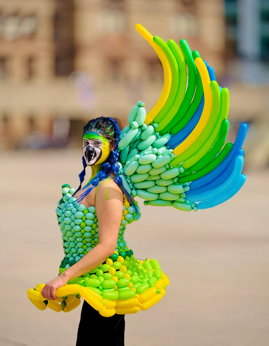 Person wearing a colorful balloon costume shaped like a parrot with a blurred background