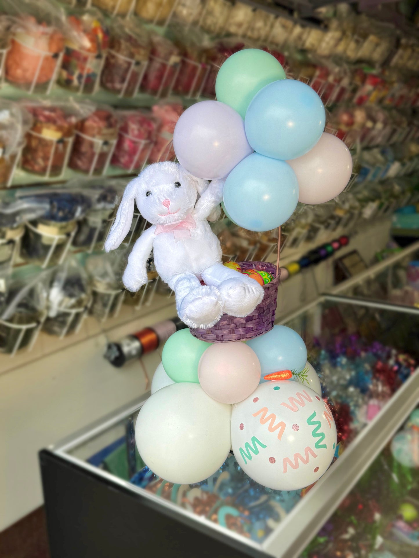 Decorative setup with pastel balloons and a plush bunny in a store setting