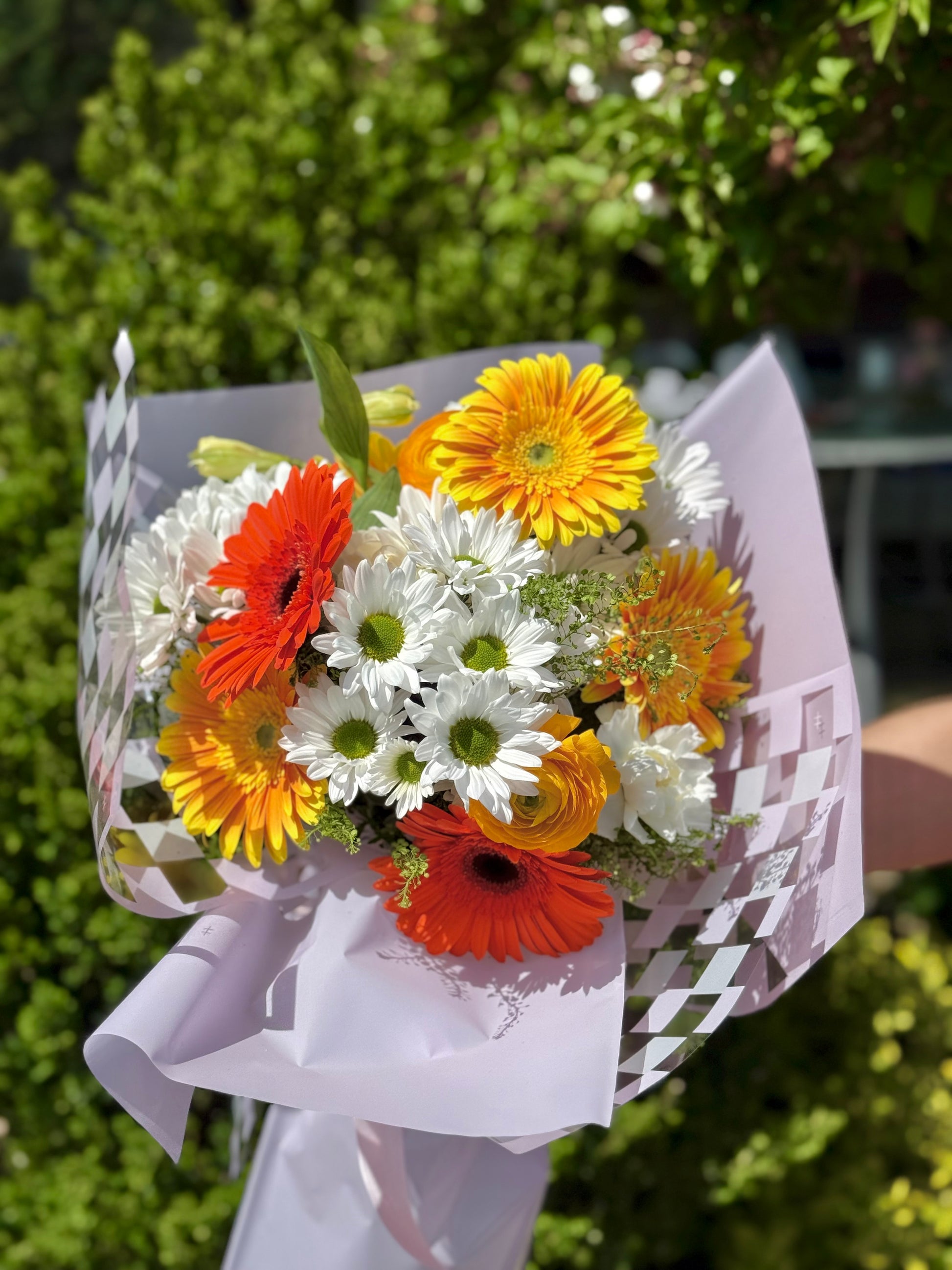 Bouquet of orange, yellow, and white flowers wrapped in paper. Mother's day present in Toronto.