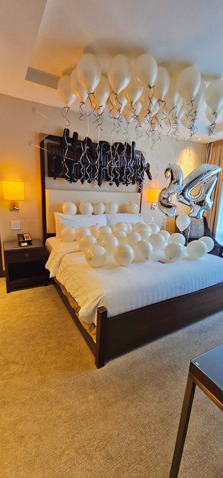 Celebration Room Setup Creamy Blush Birthday Room Decor with helium balloons, banner, and number stands.