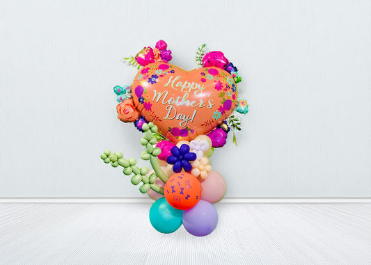 Mother’s Day balloon stand with heart balloon, lavender twisting shapes, mini flowers, and hand-styled balloon base
