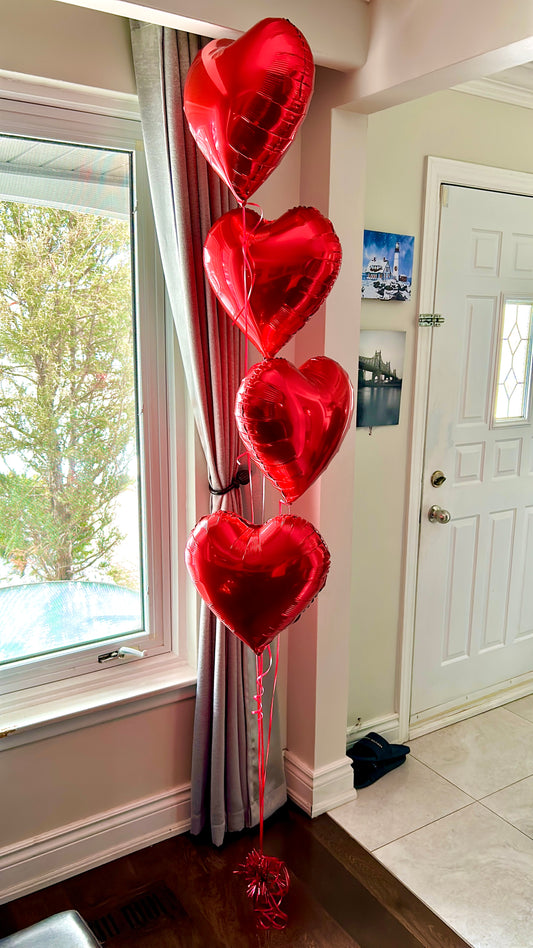 Four helium-filled red heart balloons with weight and transportation bag.