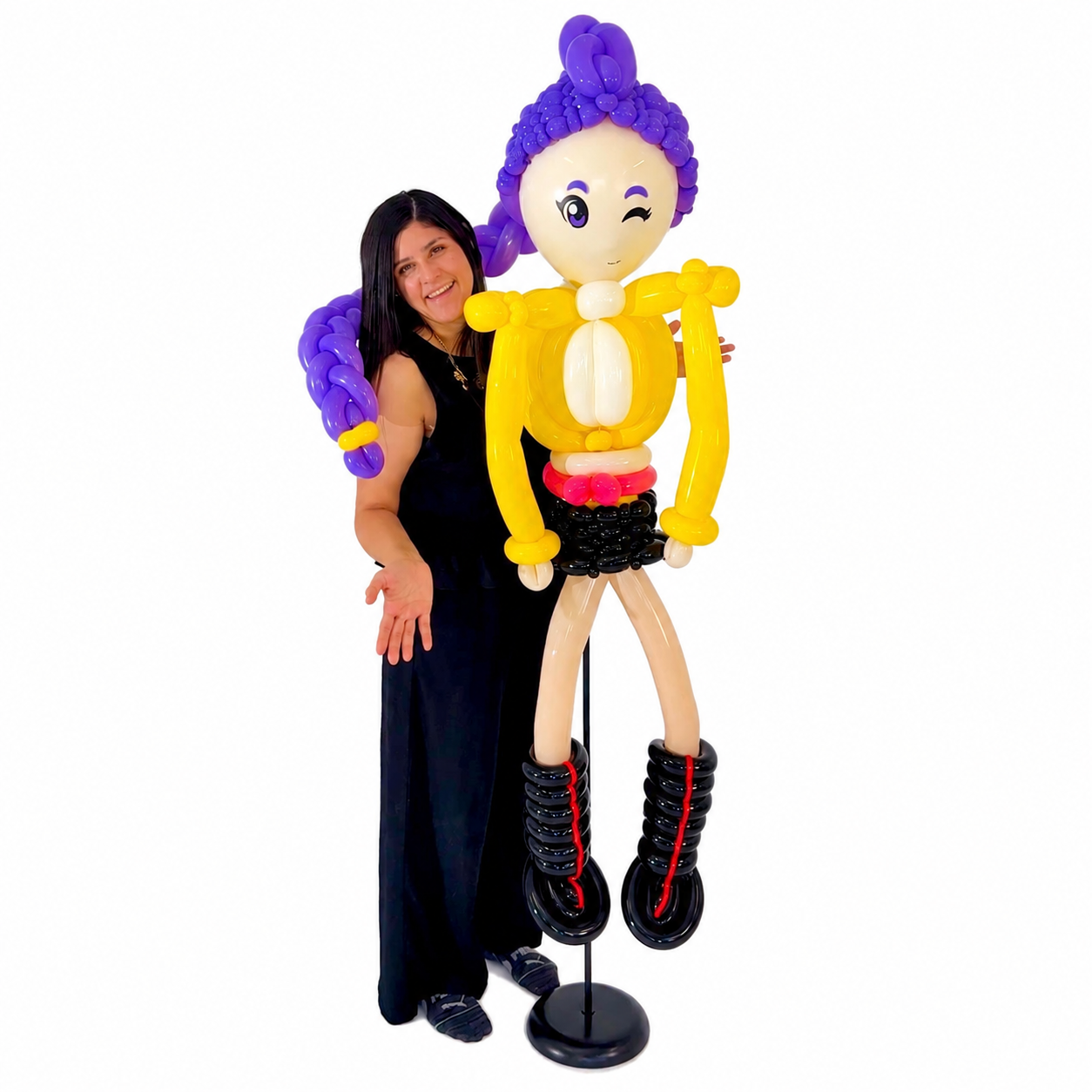 Handcrafted Rumi Kpop Demon Hunters balloon sculpture featuring purple braided hair, yellow outfit, and black boots, displayed by the artist on a white background in Toronto.