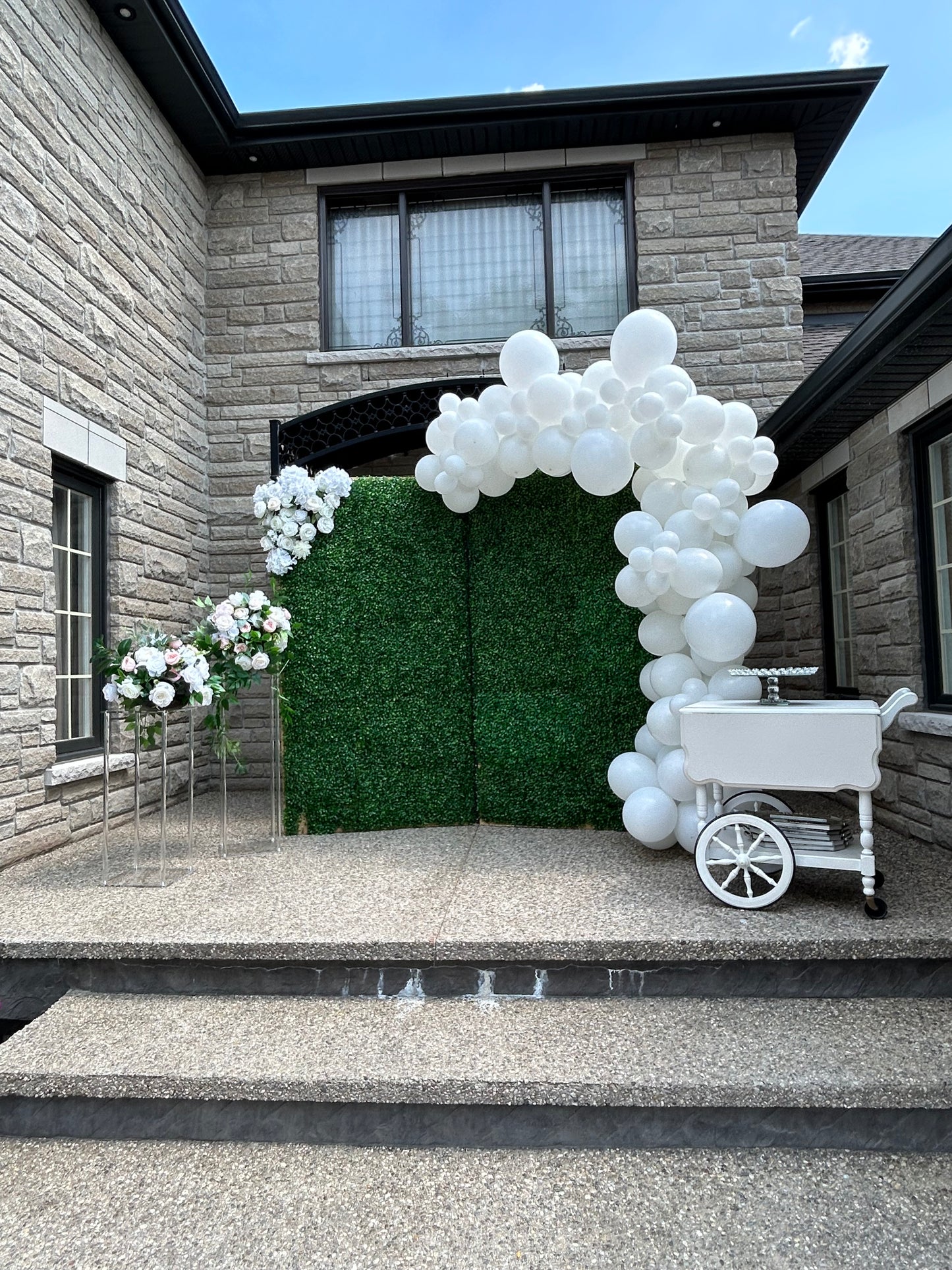 Wedding Balloon Decor featuring a greenery backdrop, organic balloon garland, and floral pedestals with dessert cart.