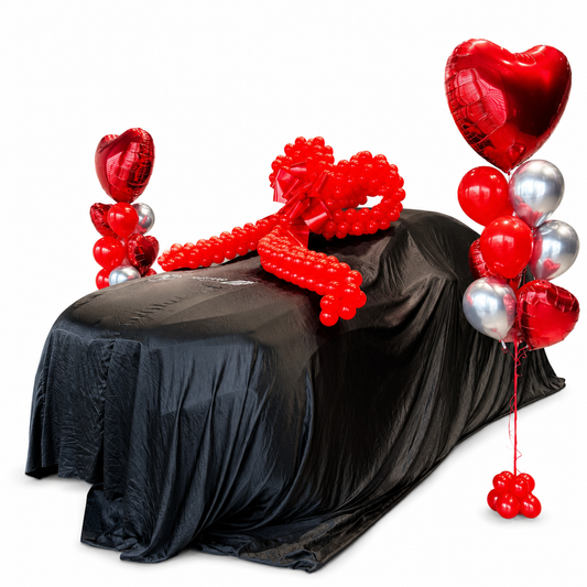 Luxury car reveal balloon surprise with red heart balloons, oversized ribbon bow, and surprise vehicle decoration in Toronto.