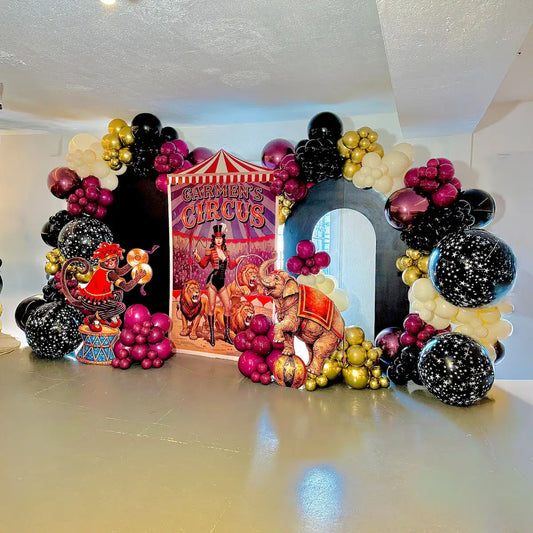 Custom circus balloon installation with black, magenta, gold and ivory garlands and a themed backdrop in Toronto.