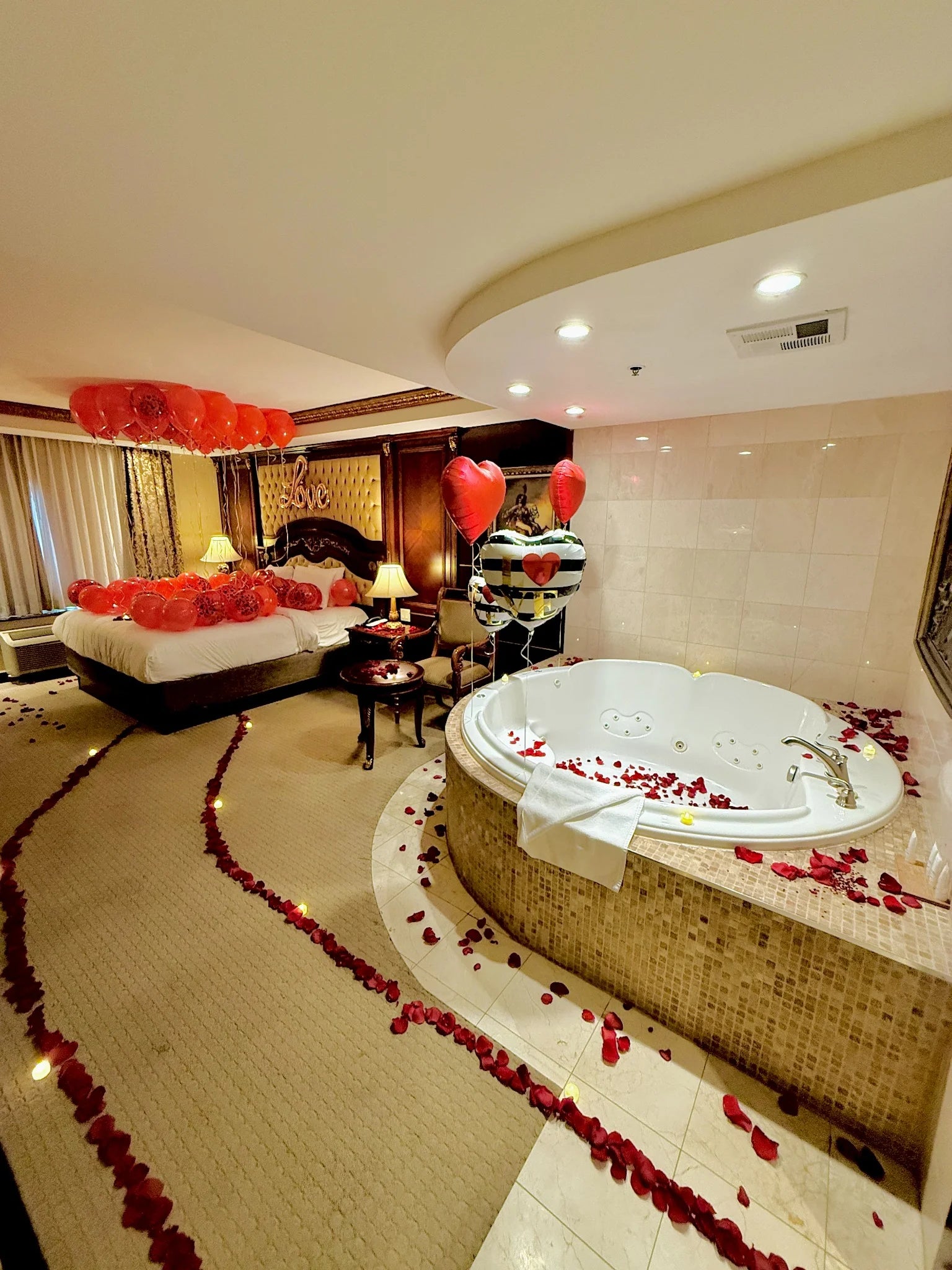 Heart balloon decor and rose petals by the jacuzzi – romantic room design in Toronto