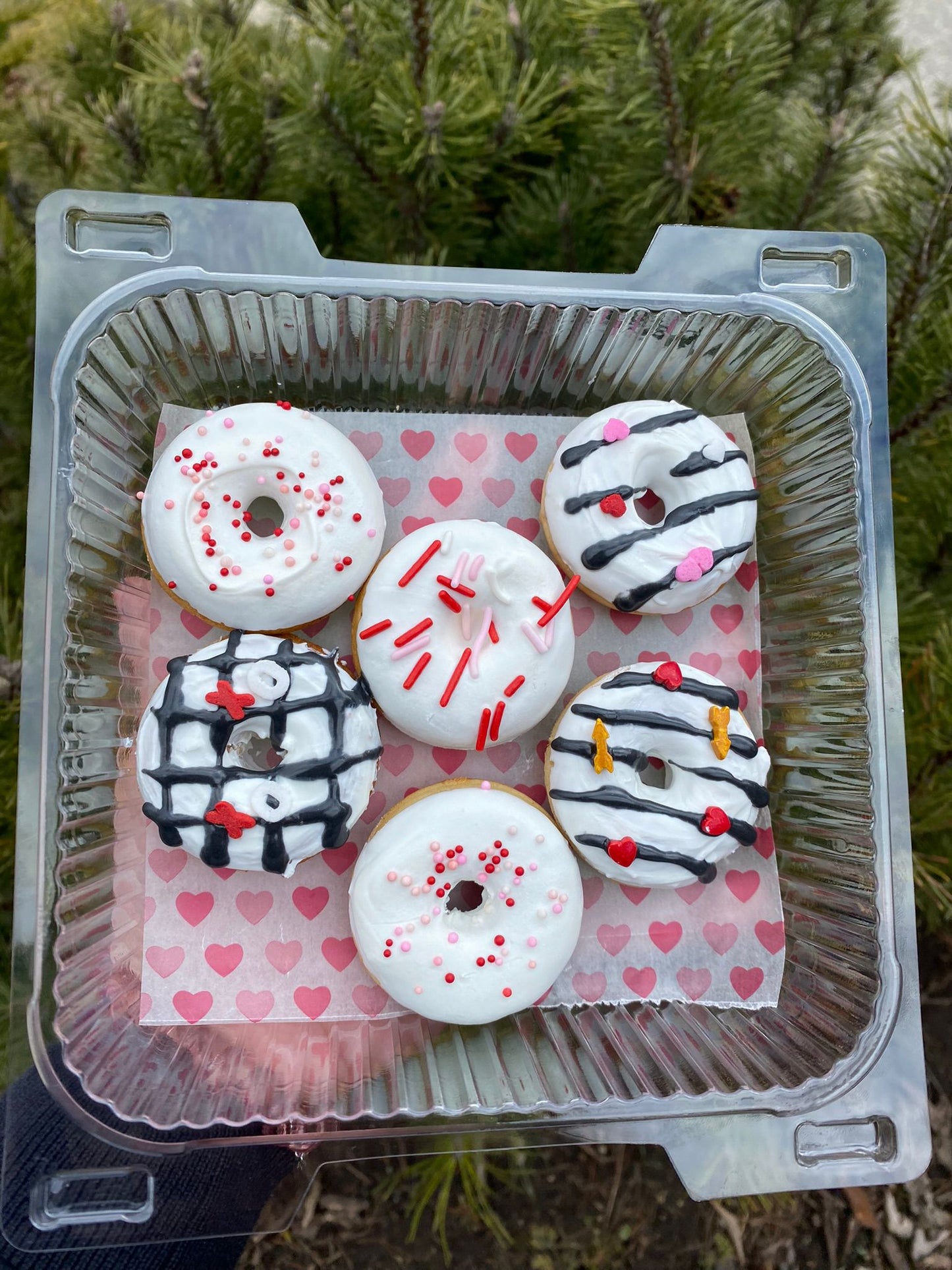 Decorative donuts in a clear container with a heart-patterned paper on a natural background