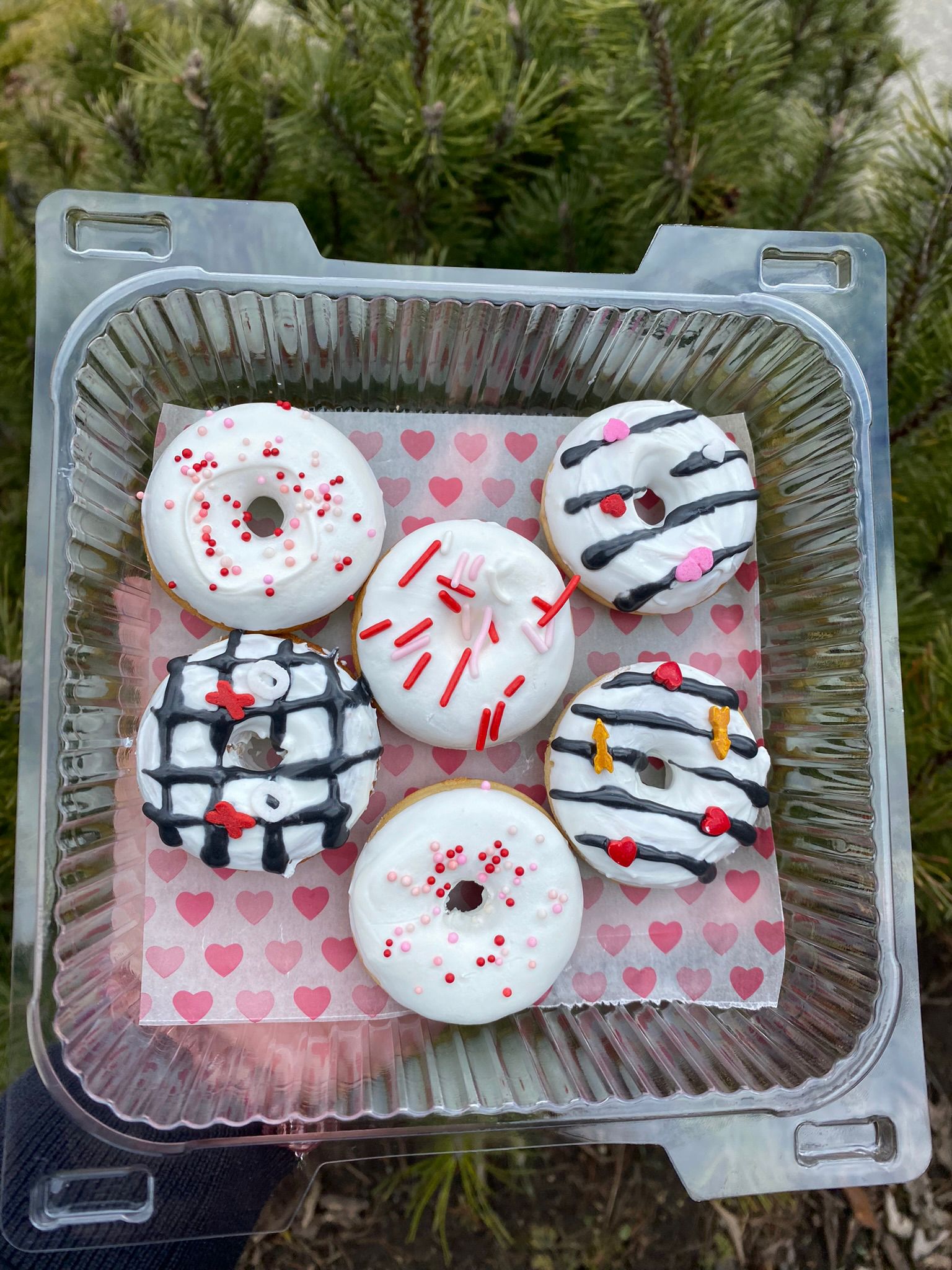 Decorative donuts in a clear container with a heart-patterned paper on a natural background