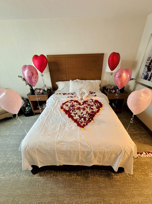 Romantic hotel room setup with heart-shaped rose petals and heart balloons in Toronto by Wooow Balloons