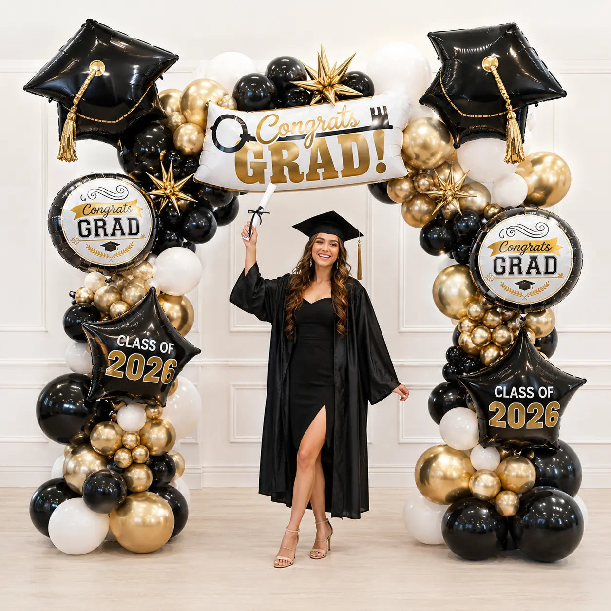 Graduate posing under black, gold and white graduation balloon arch with grad cap balloons and Class of 2026 decor in Toronto.