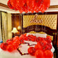 Decorative setup with red balloons and 'Love' sign on a bed in a bedroom.