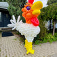 Balloon sculpture of a rooster in front of a house
