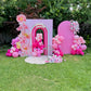 Pink birthday archway with balloons and flowers in a garden setting