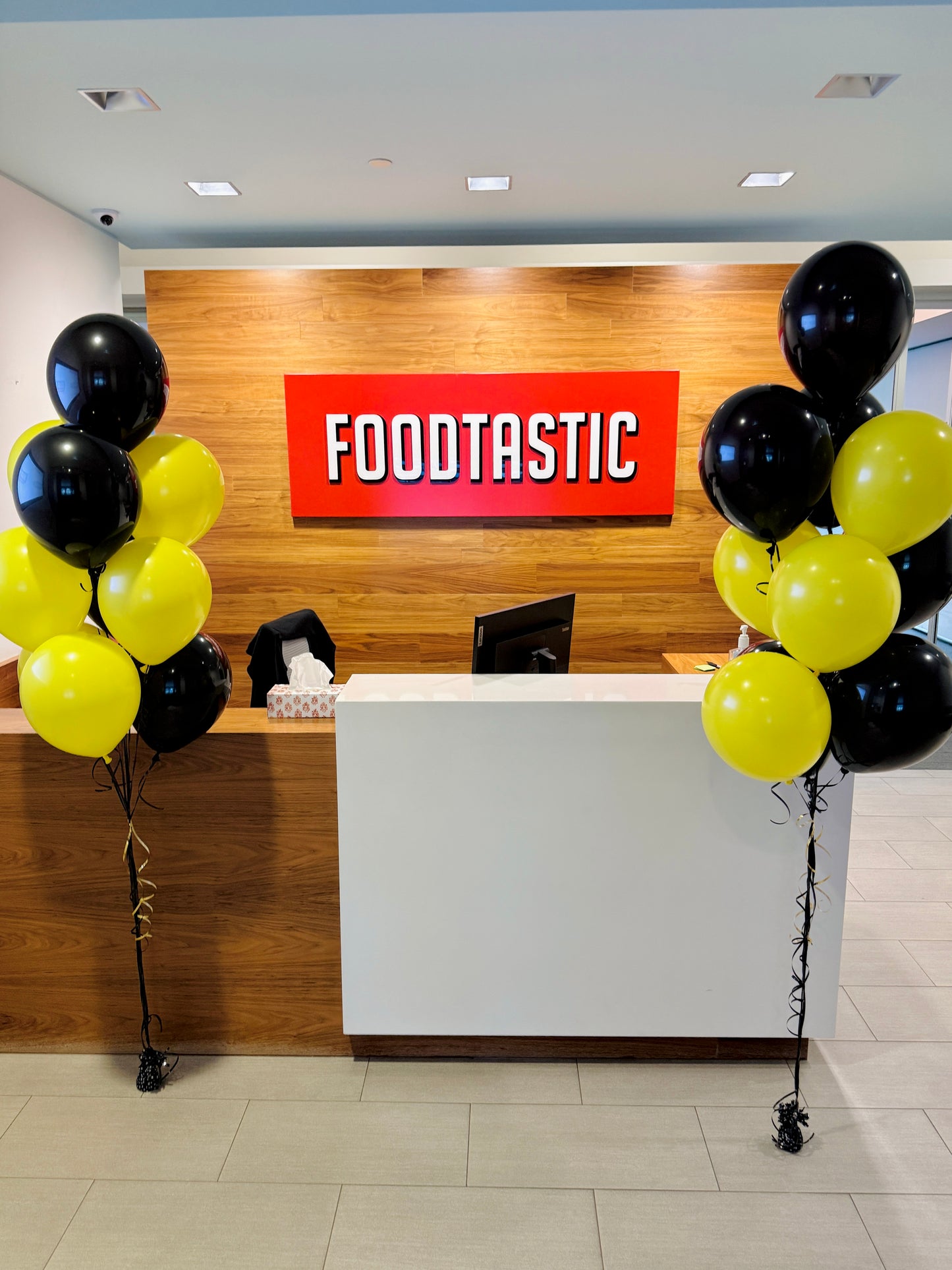 Front desk area with 'FOODTASTIC' sign and balloons in a modern interior setting