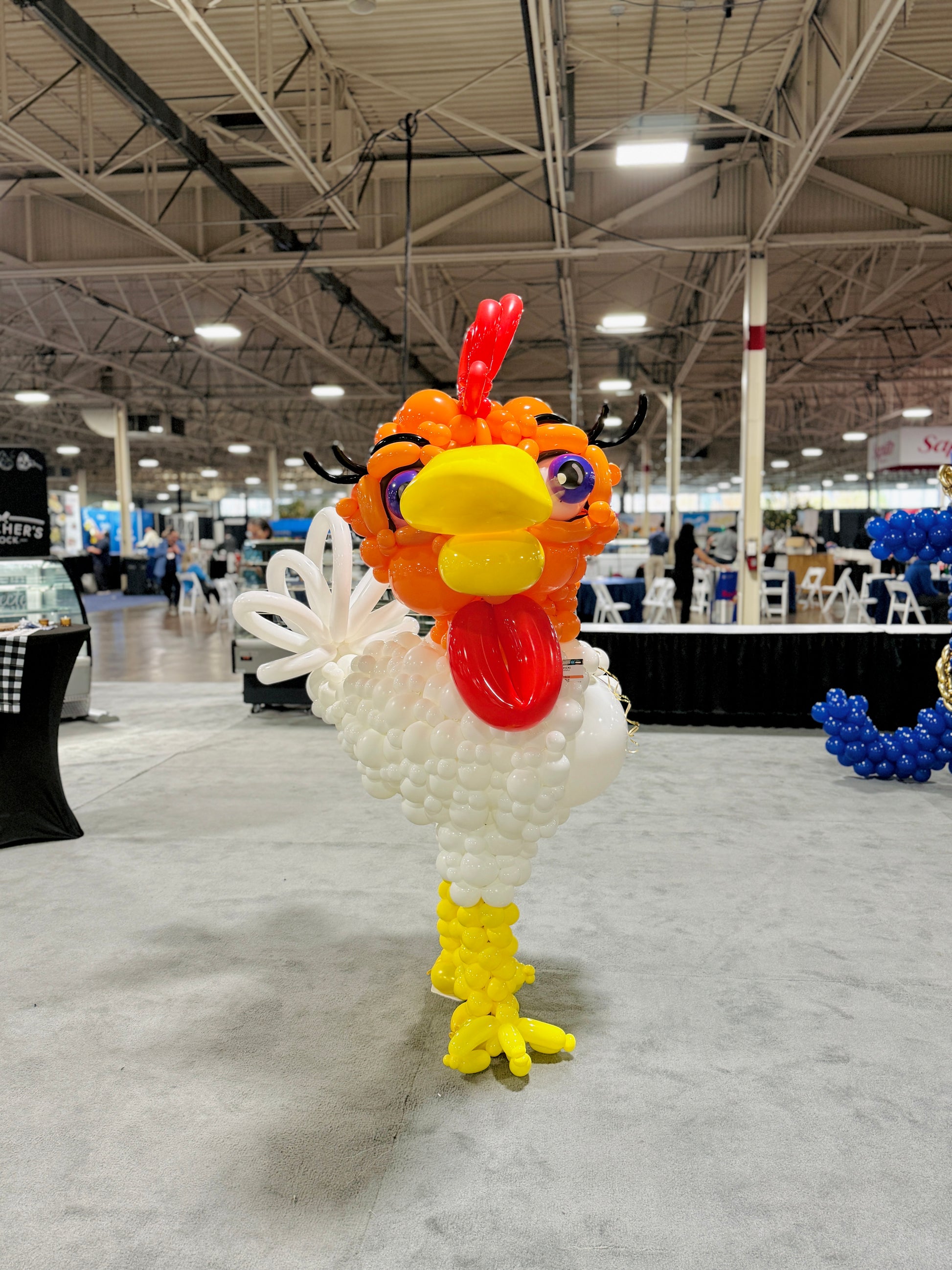 Balloon sculpture of a rooster in an indoor exhibition hall