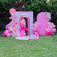 Pink birthday backdrop with balloons and flowers on a grassy area