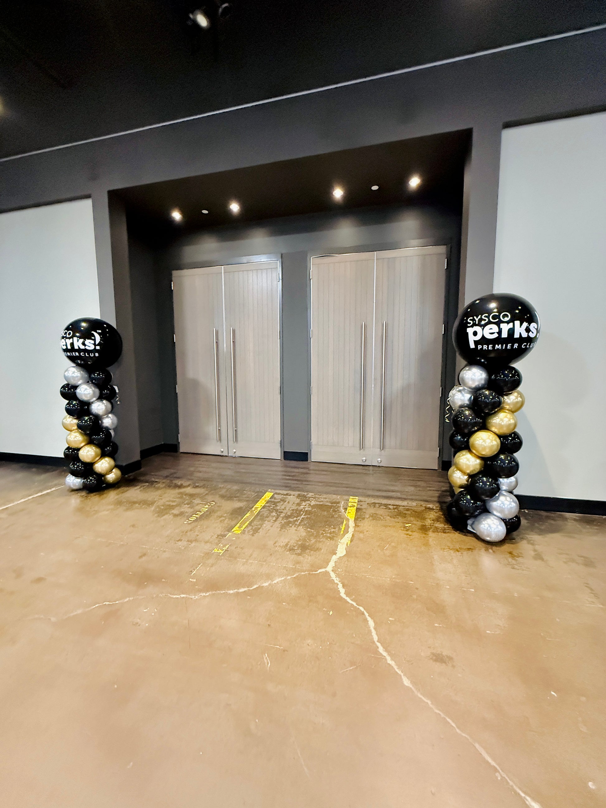 Two decorative arches with balloons on either side of a door in a room.