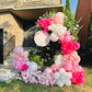 Balloon arch with pink, white, and red balloons in front of a house.