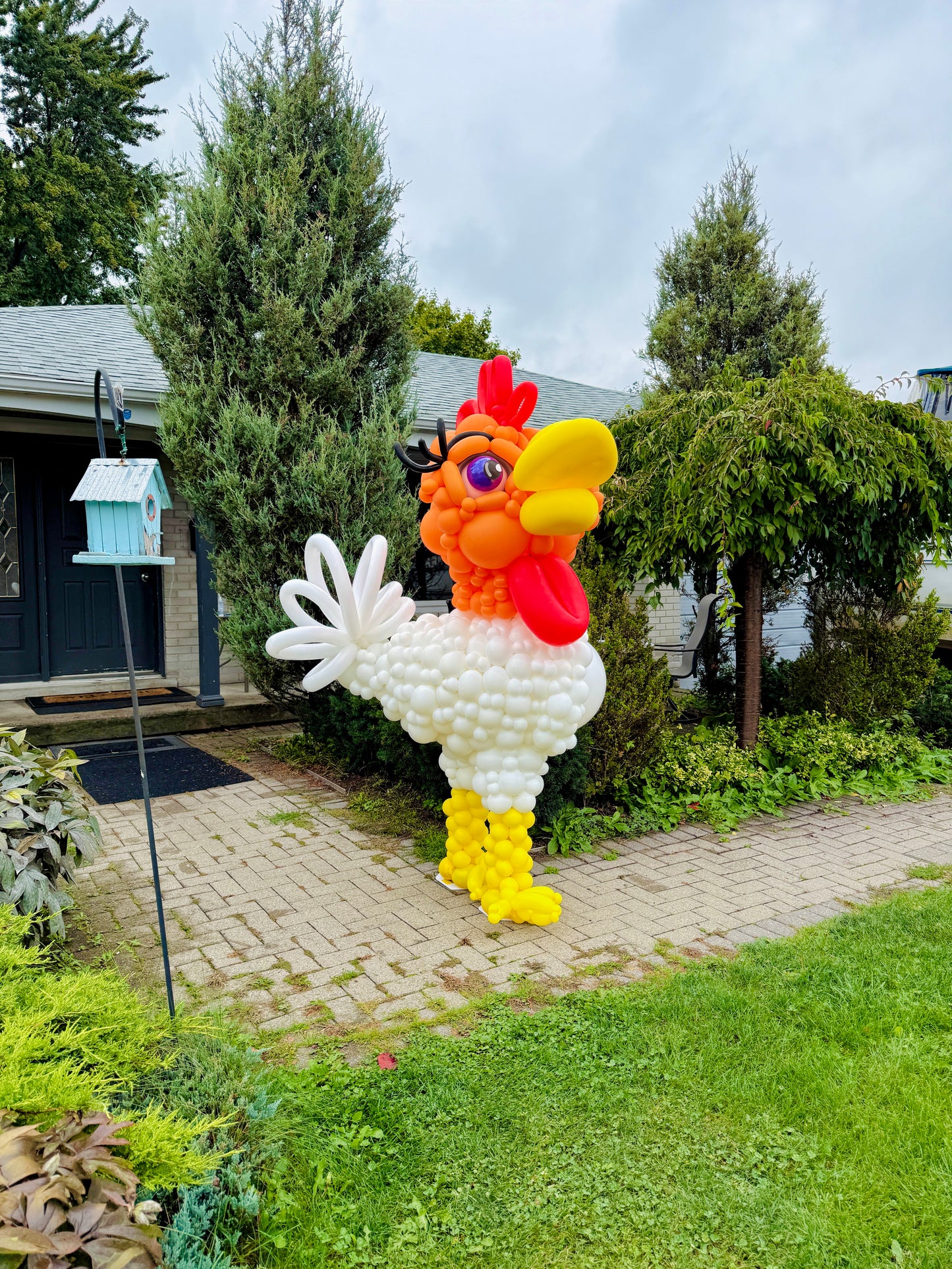 Balloon sculpture of a rooster in a garden setting