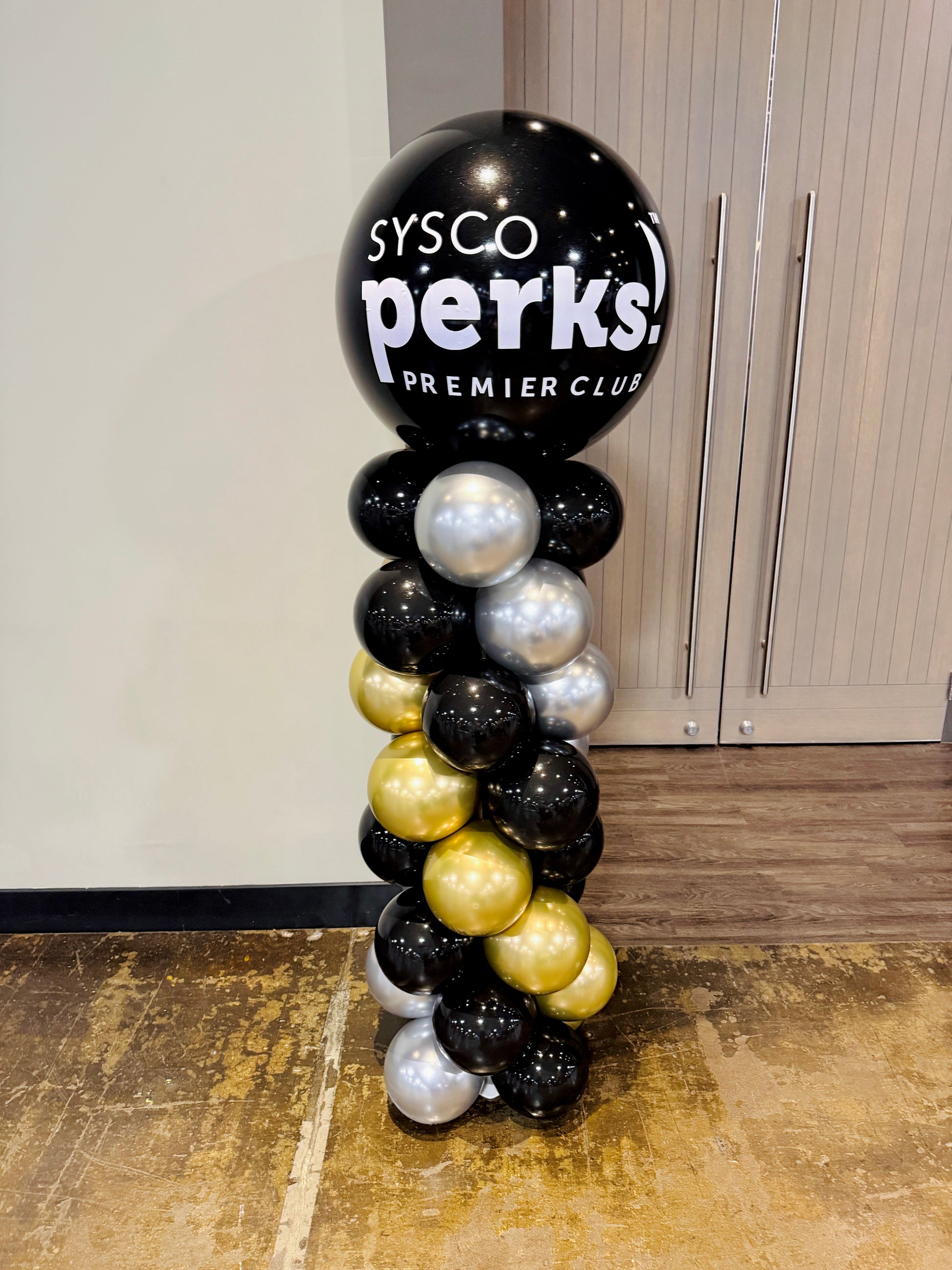 Balloon column with 'Sysco Perks! Premier Club' text against a plain wall.