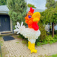 Balloon sculpture of a rooster in front of a house