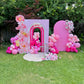 Pink birthday arch with balloons and flowers in a garden setting