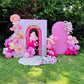 Pink birthday arch with balloons and flowers in a garden setting