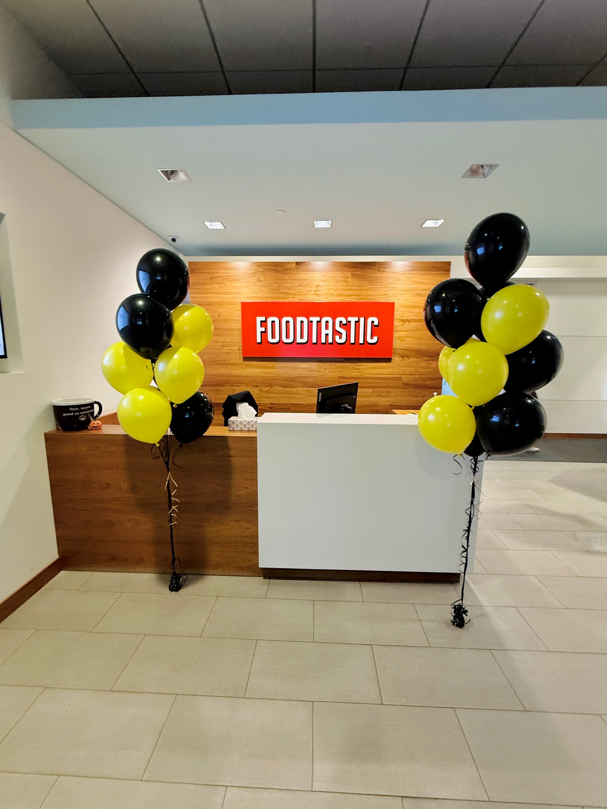 Front desk area with 'FOODTASTIC' sign and balloons in a modern interior setting