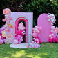 Decorative arch with pink balloons and flowers on a grassy area