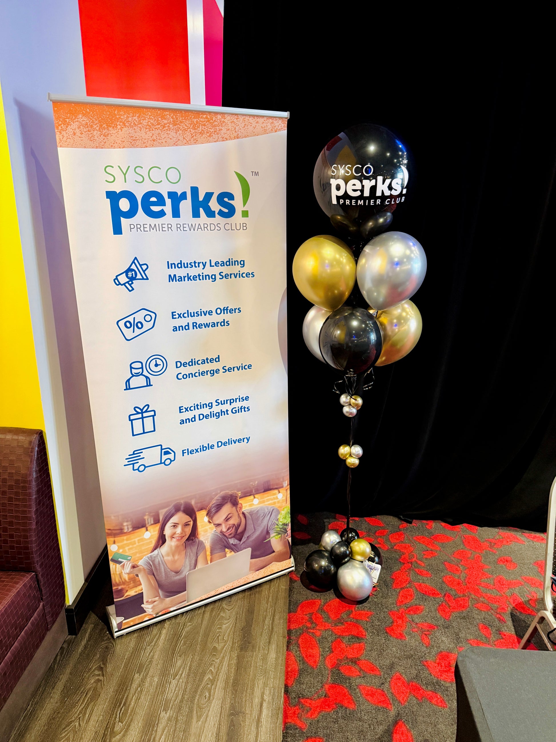SYSCO Perks promotional banner with balloons on a carpeted floor.