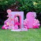 Pink birthday arch with balloons and flowers in a garden setting