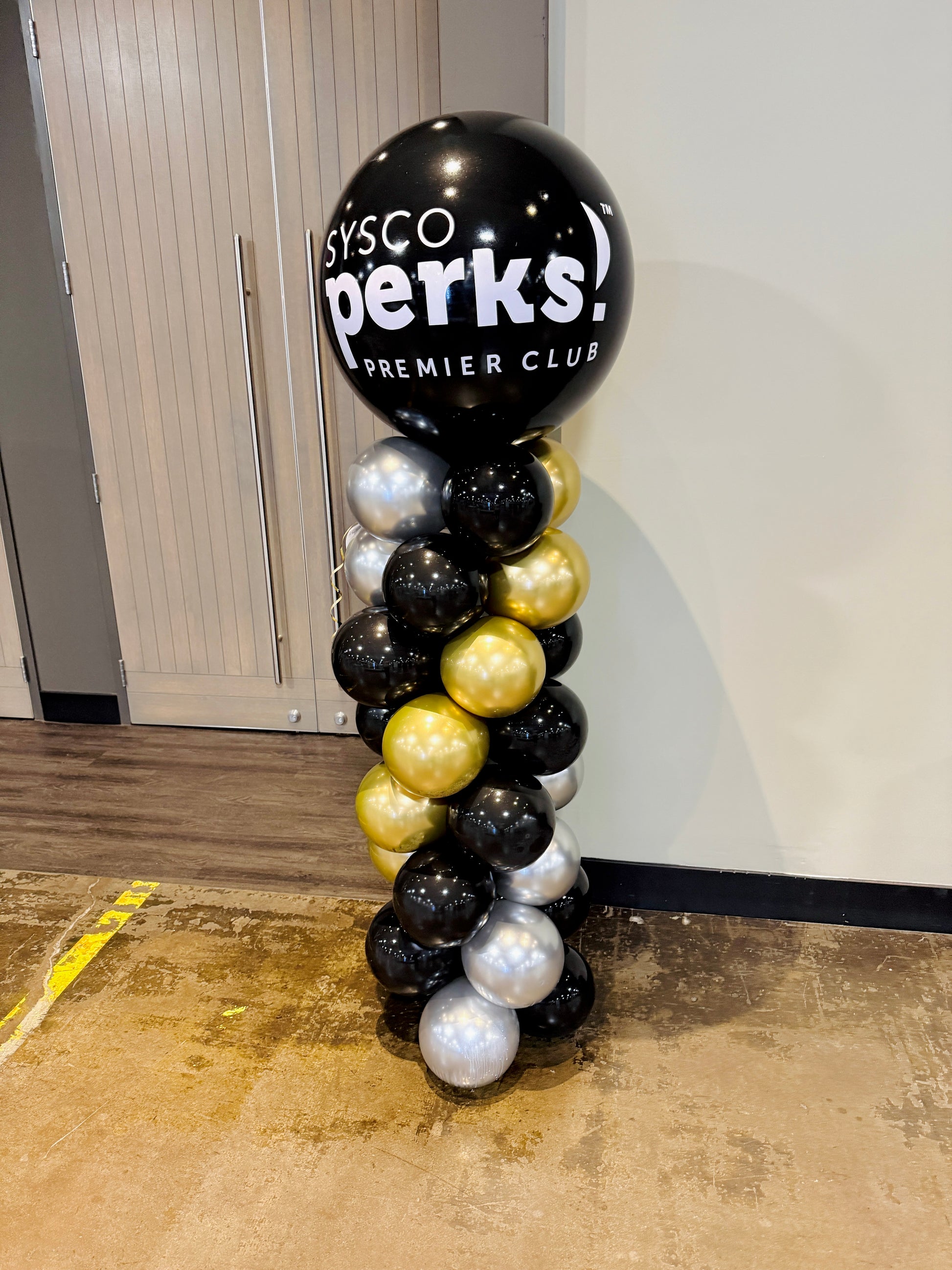 Balloon column with black, gold, and silver balloons featuring 'sysco perks!' text.