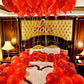 Decorative setup with red balloons and a heart-shaped arrangement on a bed, featuring the word 'Love'.