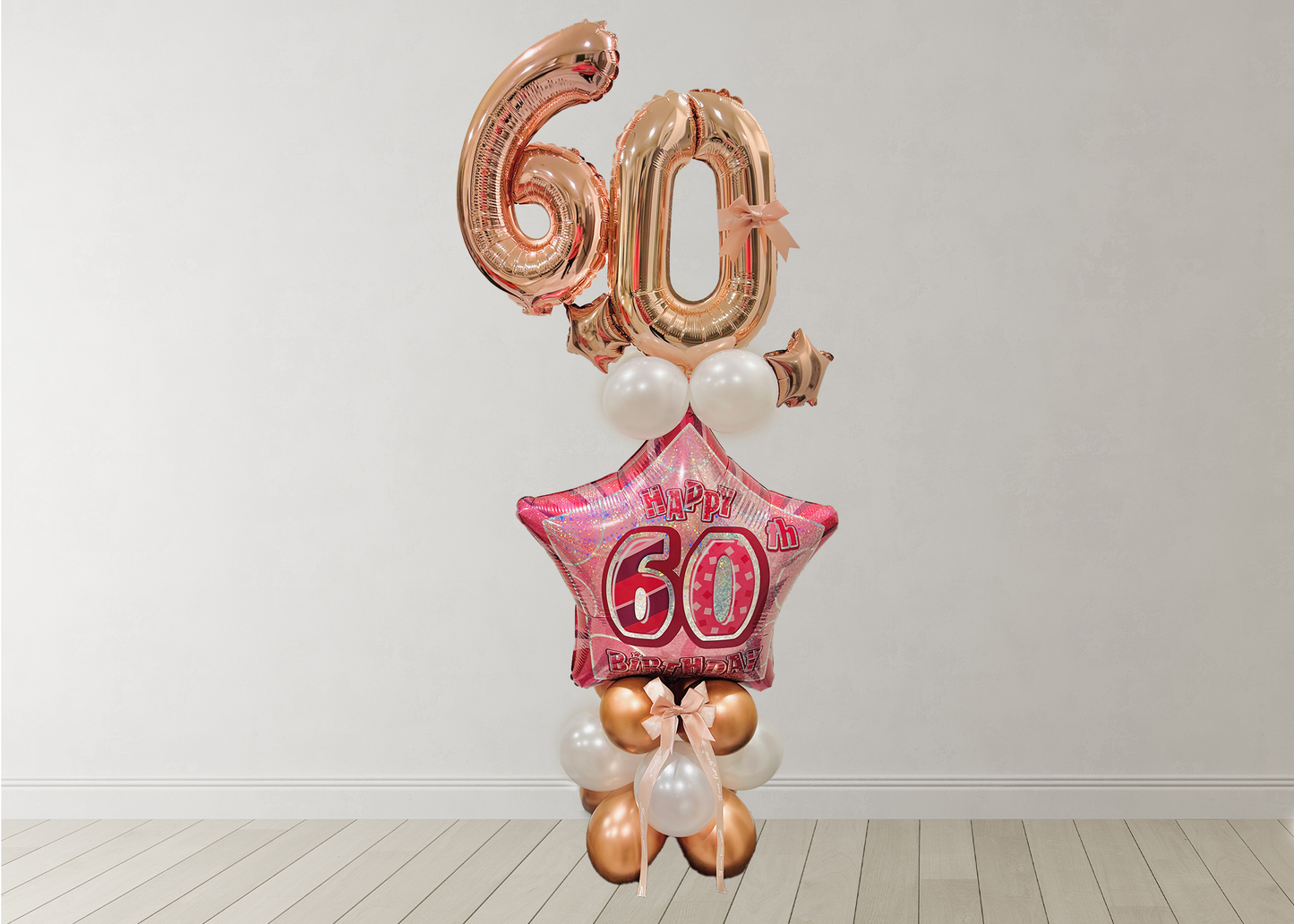 Balloon arrangement with '60' on a star-shaped balloon against a white wall.