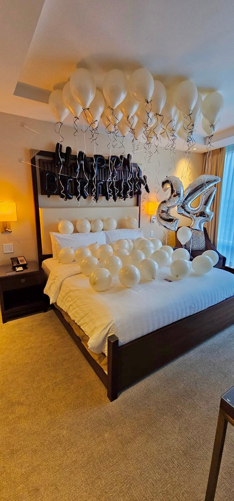 Birthday Celebration Room Setup Creamy Blush Birthday Room Decor with helium balloons, banner, and number stands.