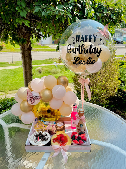 Birthday gift set with balloons and snacks on a table outdoors