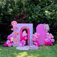 Pink balloon arch and floral decorations in a garden setting