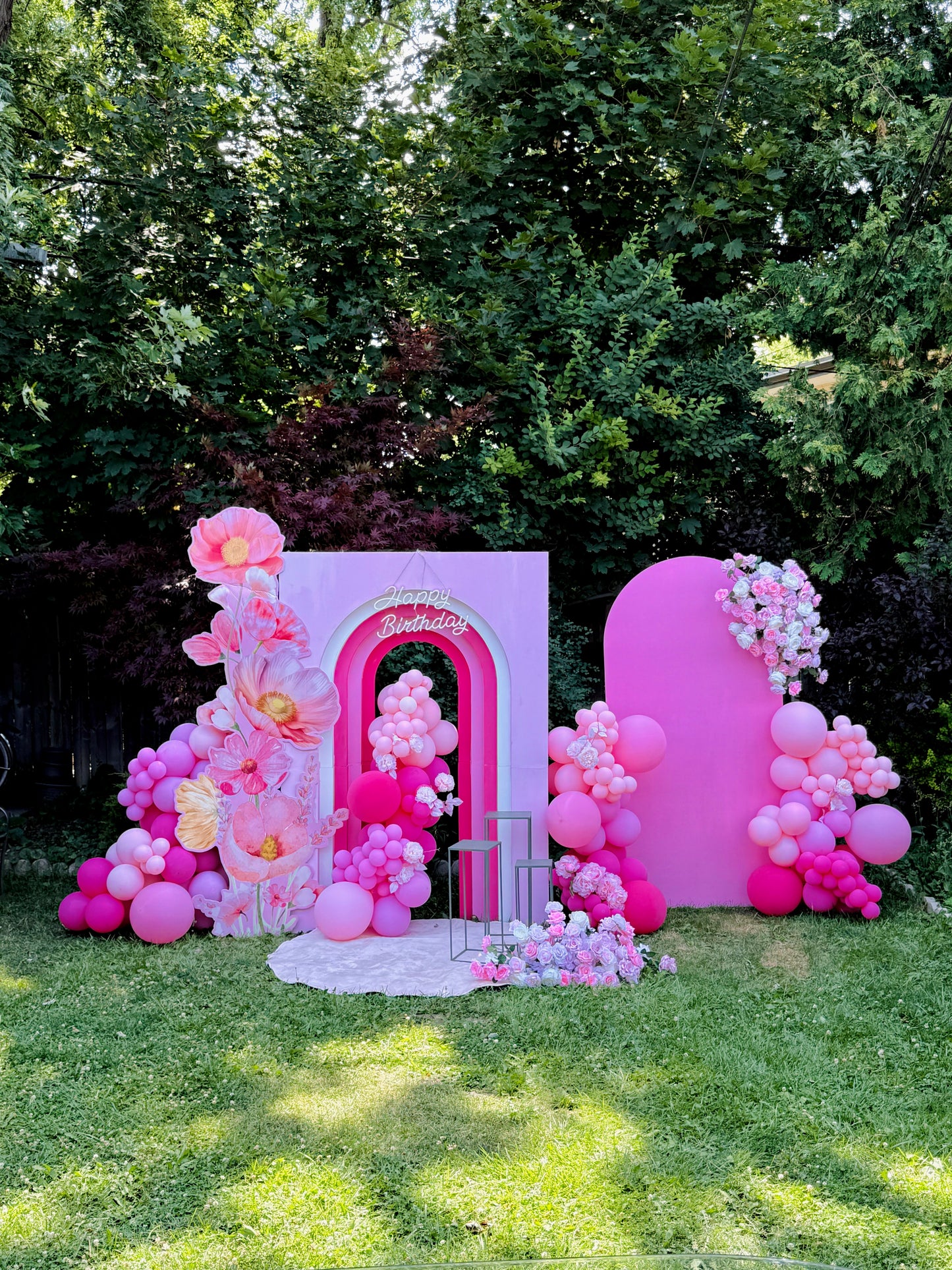 Pink balloon arch and floral decorations in a garden setting