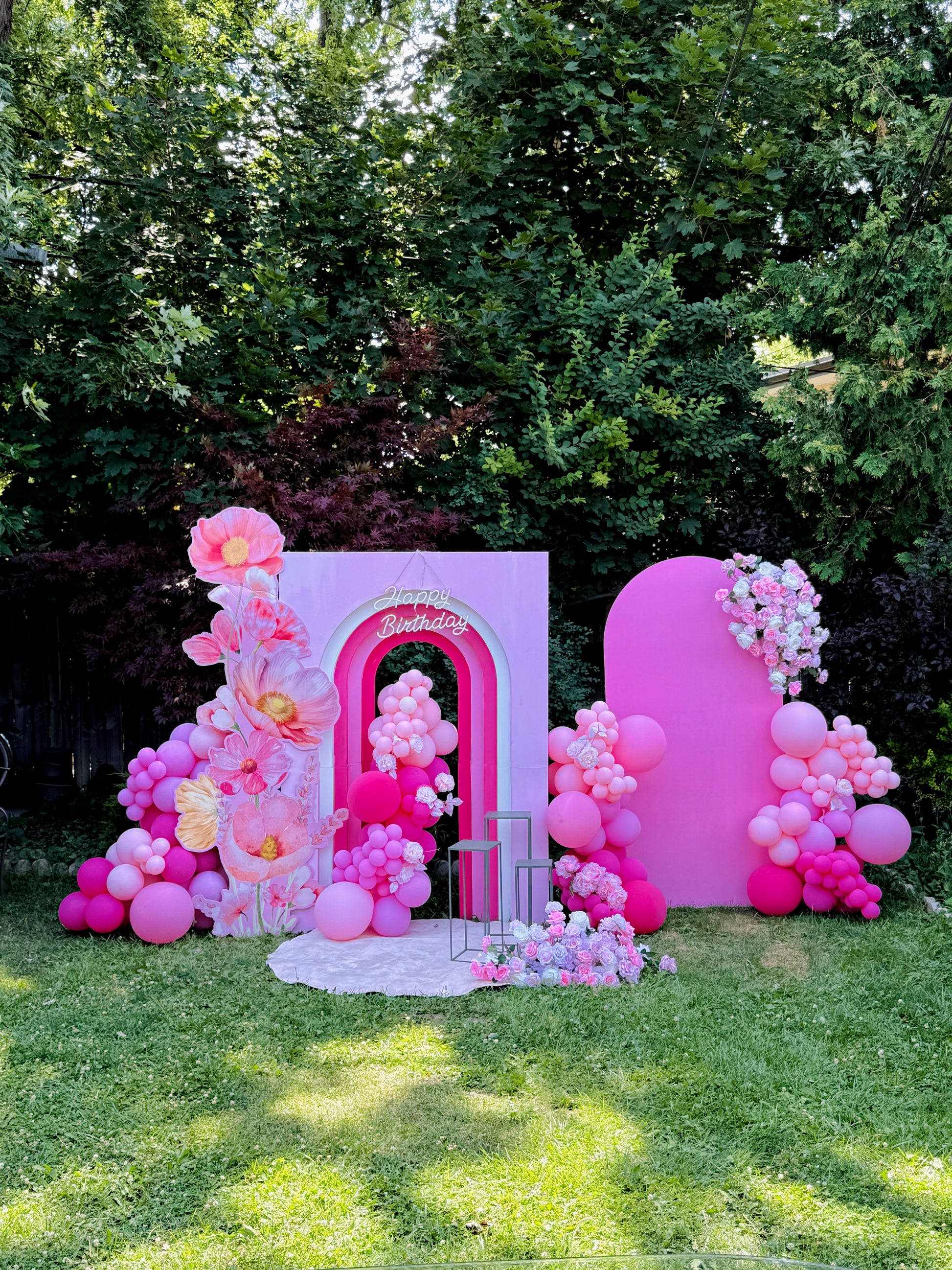 Pink balloon arch and floral decorations in a garden setting