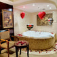 Luxurious bathroom with a Jacuzzi, heart-shaped balloons, and rose petals.