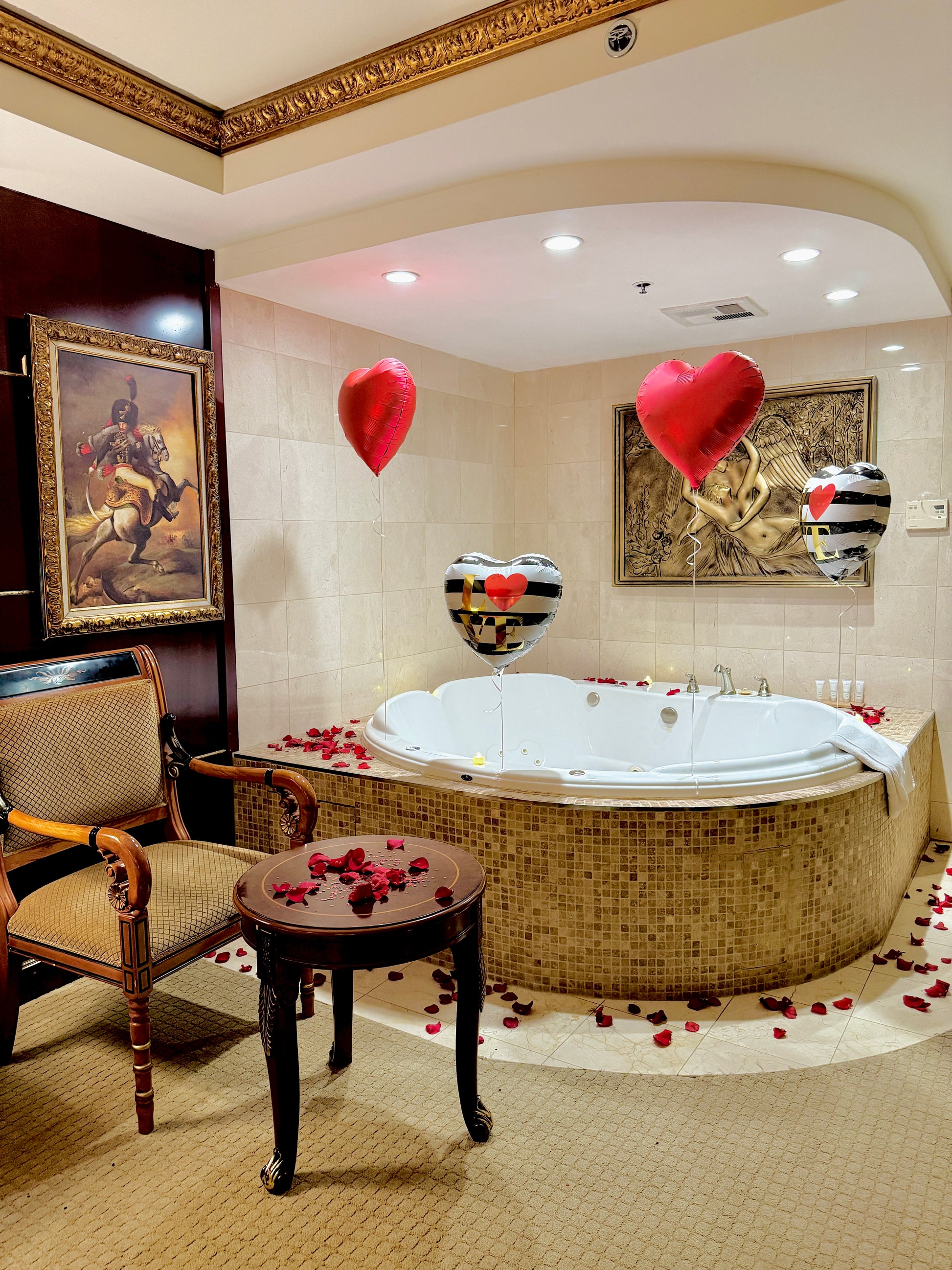 Luxurious bathroom with a Jacuzzi, heart-shaped balloons, and rose petals.