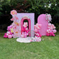 Decorative birthday arch with pink balloons and flowers on a grassy area