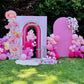 Decorative arch with pink balloons and flowers in a garden setting