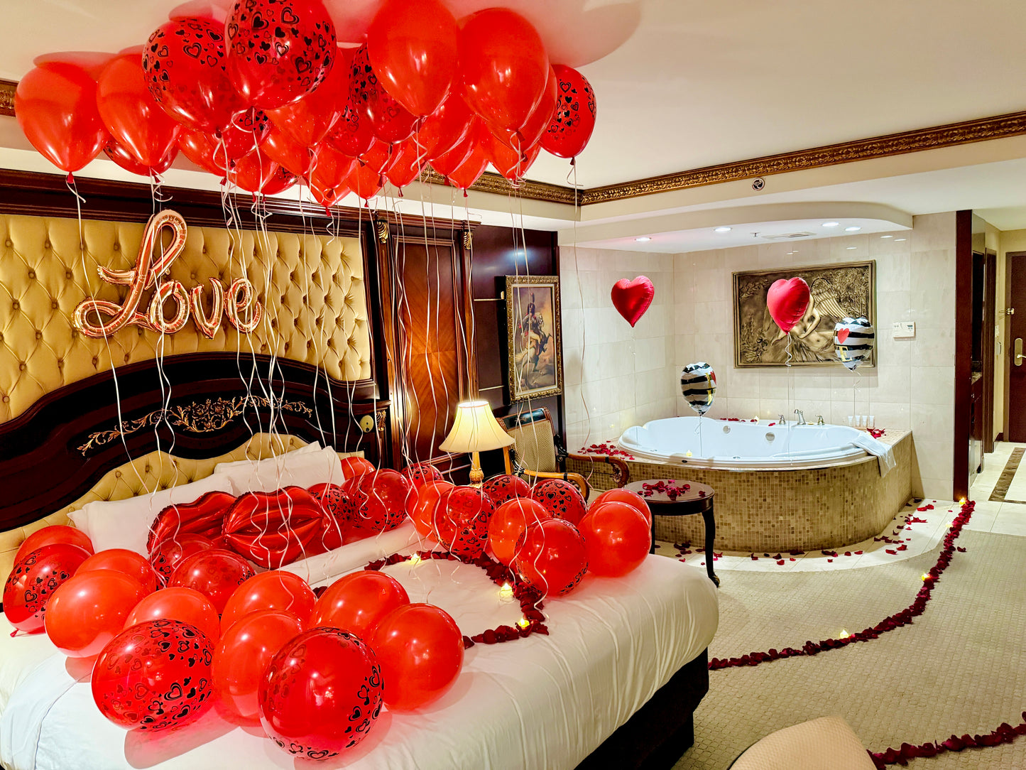 Decorated bedroom with red balloons, 'Love' sign, and a Jacuzzi.