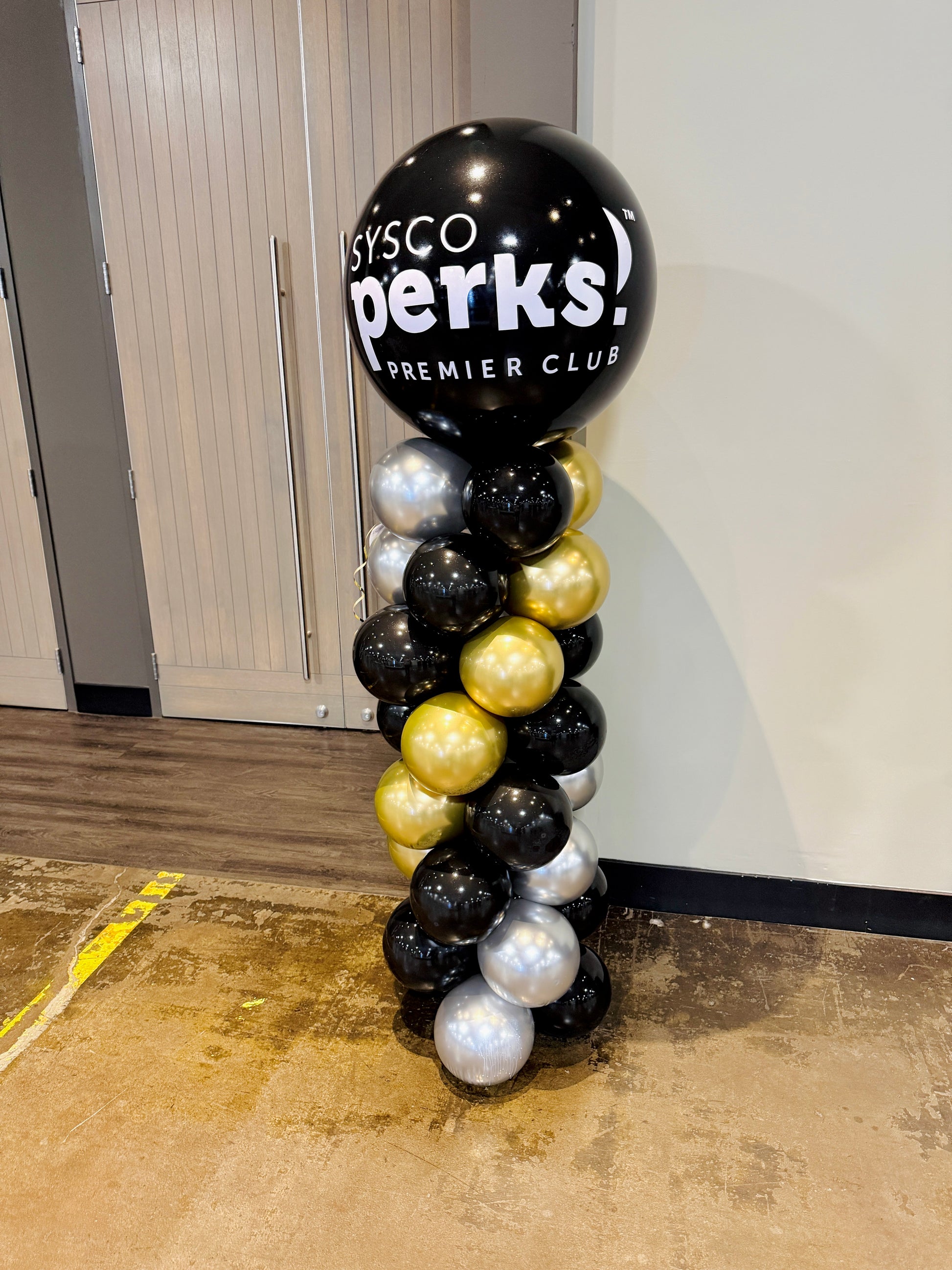 Balloon column with Sysco Perks Premier Club logo in a room.