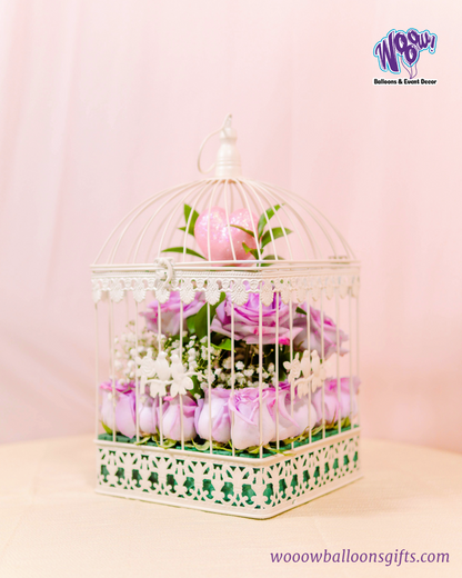 Enchanted Love Cage with fresh lavender roses and a sparkling pink heart inside a white decorative birdcage.