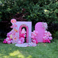 Decorative arch with pink balloons and floral arrangements in a garden setting