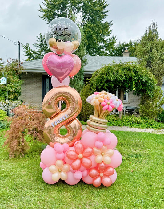 Decorative balloon arrangement with number '8' and floral shapes on a grassy lawn.